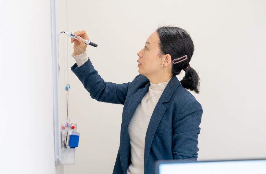 Professor Wang Mengqiu at a white board, explaining how she uses deep learning techniques to better track algal blooms
