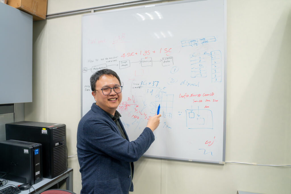 Professor Wu stands in front of a whiteboard